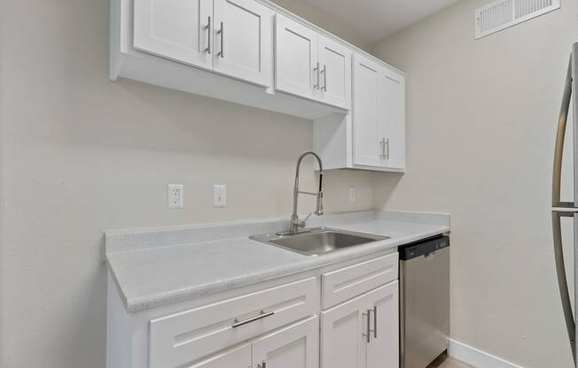 an empty kitchen with white cabinets and a sink and refrigerator