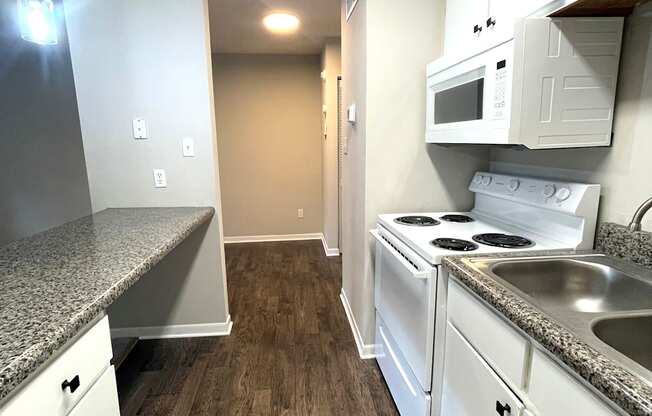 A kitchen with white cabinets and a granite countertop.