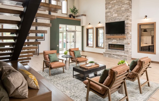 A living room with a stone fireplace and a staircase.