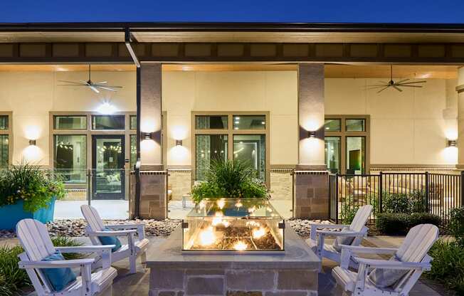 A patio with a fire pit and chairs.