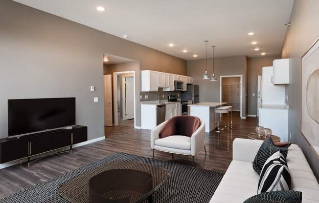 a living room and kitchen with a couch and a tv. Fargo, ND 29 West Apartments