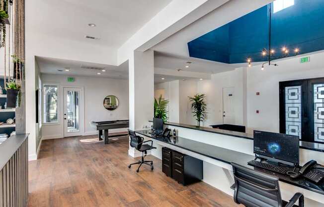 A modern office space with a long desk, chairs, and a computer.