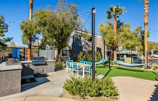 a patio with chairs and a grill and a hammock in front of a building