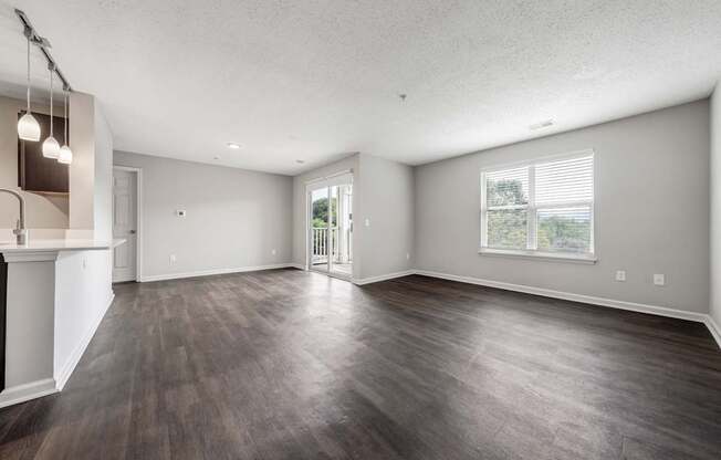 A spacious room with wood flooring and a fireplace on the left side.