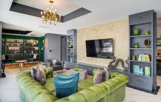 A living room with a green couch and a chandelier.