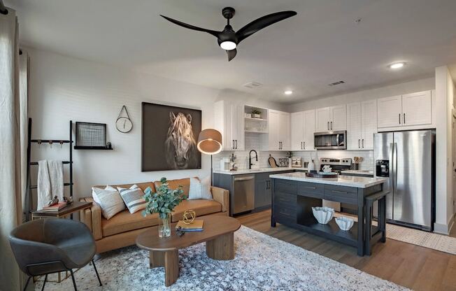a living room with a kitchen and a ceiling fan