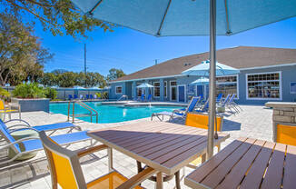 tables and chairs around a pool with the clubhouse in the background at Reserve at Temple Terrace, Temple Terrace, FL