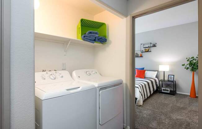 a laundry room with a washer and dryer and a bedroom with a bed