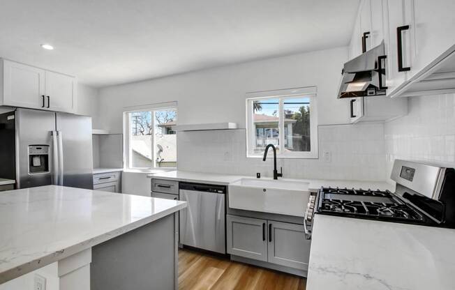 a white kitchen with stainless steel appliances and white counter tops