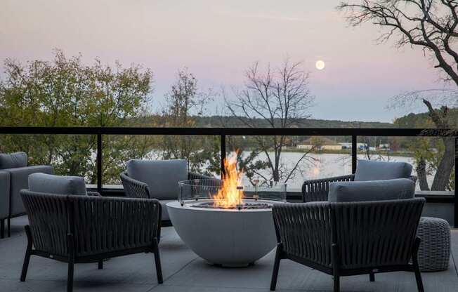 A fire pit sits in the middle of a patio surrounded by chairs.
