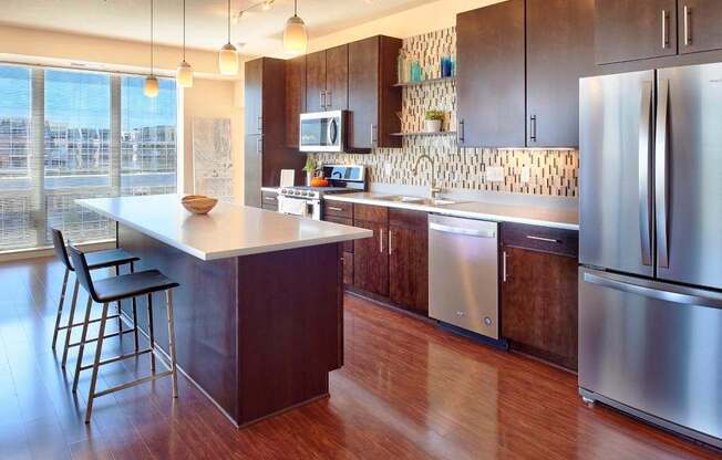 A modern kitchen with a wooden floor and stainless steel appliances.