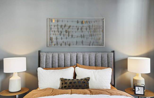 a bedroom with a bed with pillows and a painting on the wall