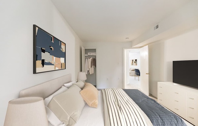 A bedroom with a bed, a lamp, and a painting on the wall.