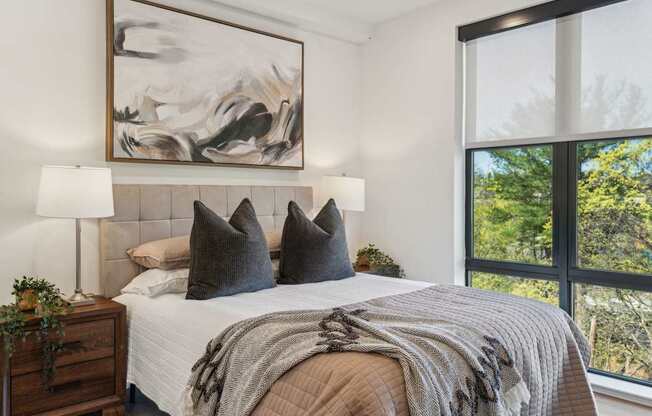 A bedroom with a large bed, a lamp, and a painting on the wall.