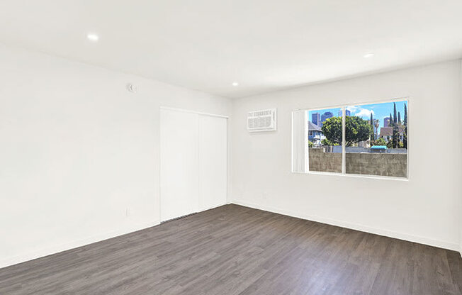 A room with a window showing a view of a cityscape.