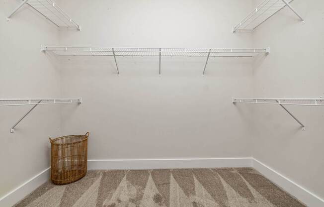 A room with white walls and a patterned carpet with a basket on the floor.