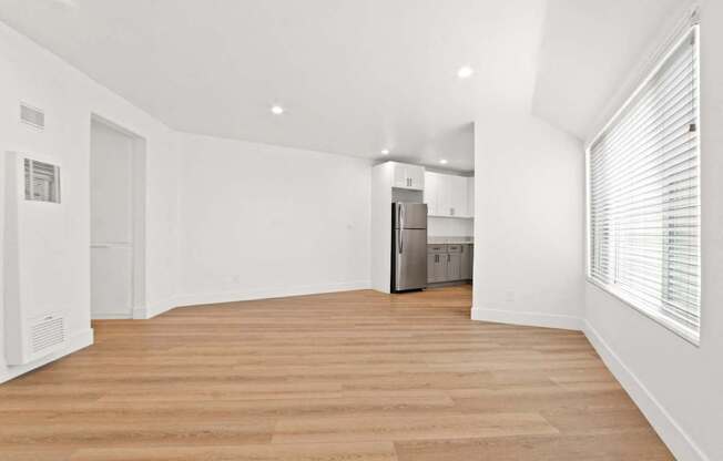 a renovated living room with a wood floor and a kitchen