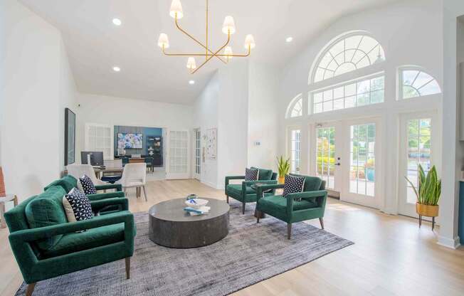 A living room with green chairs and a chandelier.