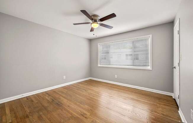 A room with a ceiling fan and wooden flooring.