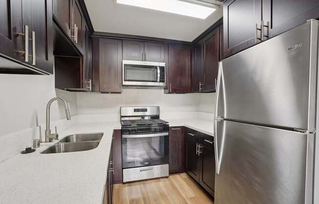 A modern kitchen with dark wood cabinets and stainless steel appliances.