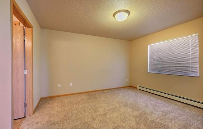 the upstairs bedroom has a large window and carpeted floor. Fargo, ND East Bridge Apartments