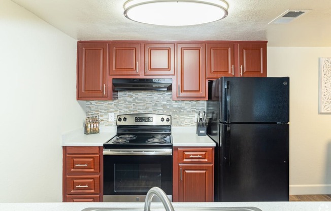 a kitchen with cherry cabinets and black appliances