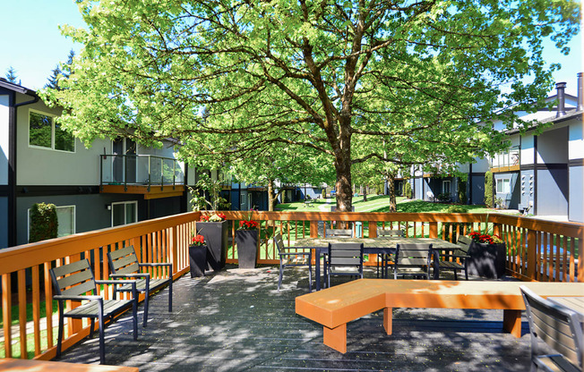 an outdoor patio with a tree and tables and chairs