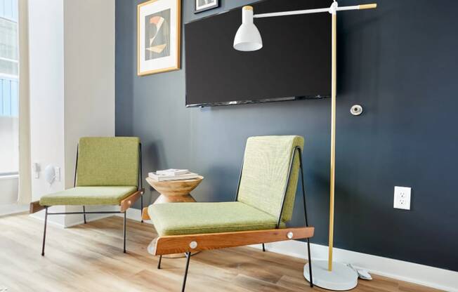 a living room with two chairs and a lamp and a television