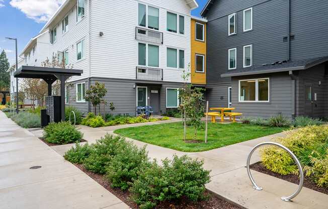 a view of a courtyard between two buildings with a yellow picnic table