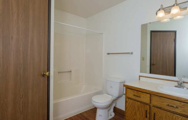 a bathroom with a toilet and a sink and a shower. Fargo, ND Park Circle Apartments.