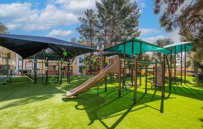 A playground with a green slide and a black canopy.
