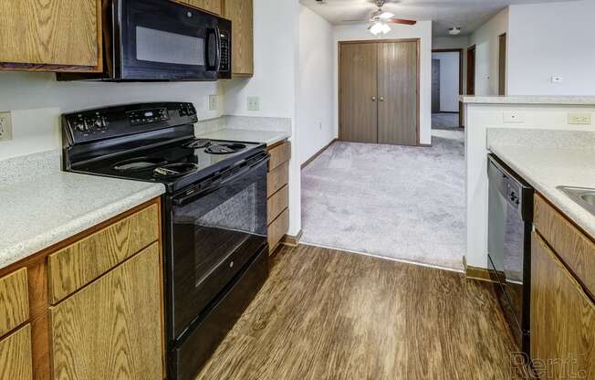 a kitchen with a stove and a microwave and a hallway with a door