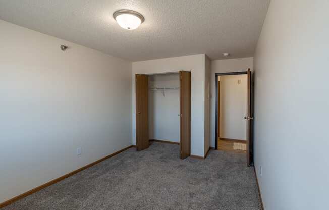 Fargo, ND Parkside Apartments. A bedroom with a carpeted floor and a door to a closet