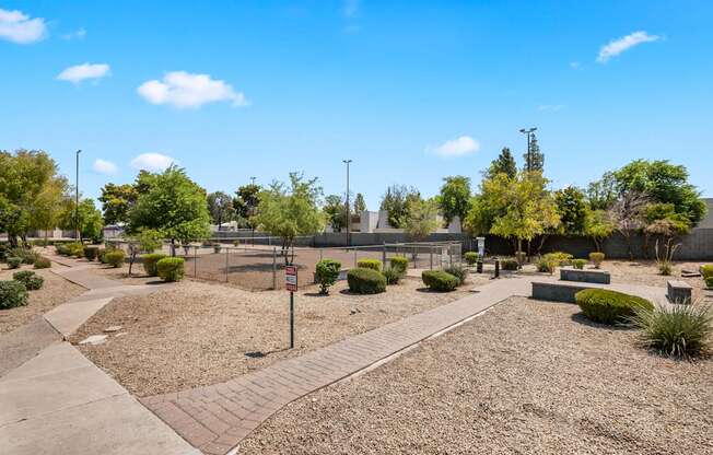 a park with benches and trees and a fence