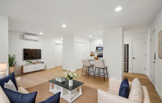 A living room with a white couch, a black coffee table, and a television.