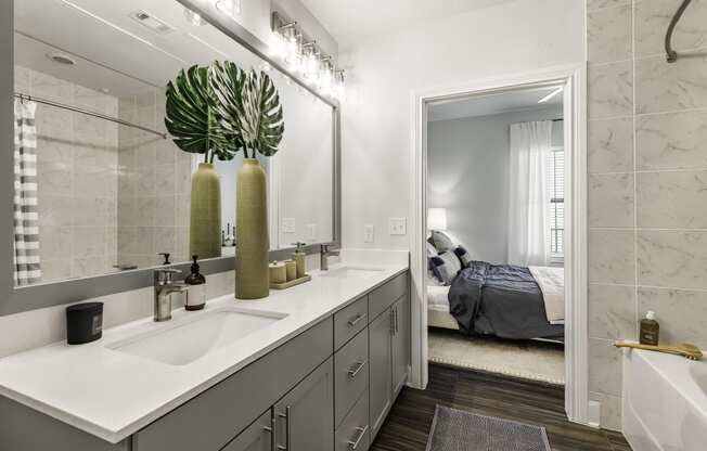 a bathroom with gray cabinets and a large mirror