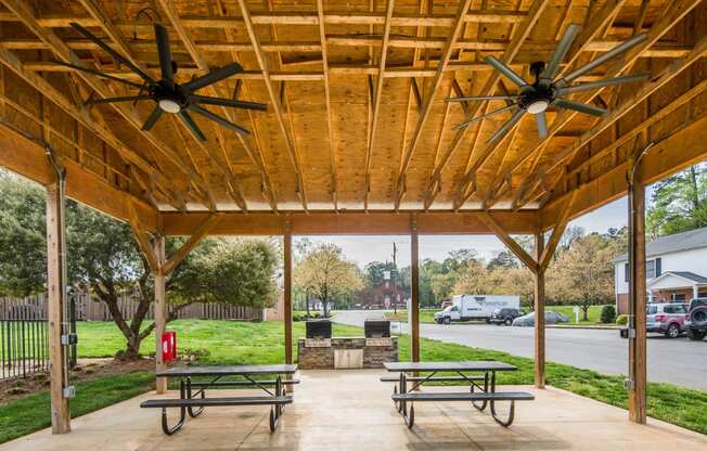 two picnic tables under a pavilion with two ceiling fans