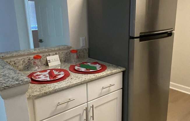 a kitchen with white cabinets and a stainless steel refrigerator