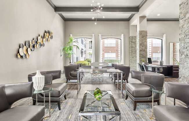 A modern living room with a glass coffee table and leather chairs.