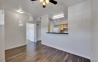 an empty living room with a ceiling fan and a kitchen