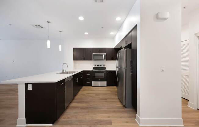 A modern kitchen with dark wood cabinets and stainless steel appliances.