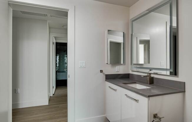 A bathroom with a sink, mirror and cabinet.