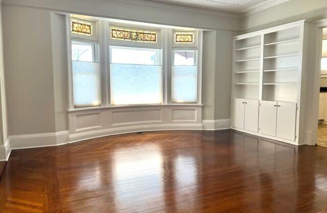 a living room with a wooden floor and a large window