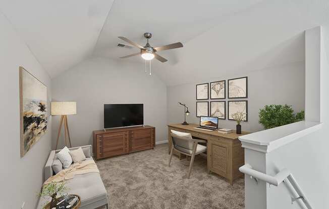 a home office in a loft with a ceiling fan and a flat screen tv