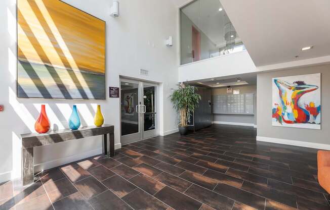 A hallway with a large painting on the wall and a bench with three vases on it.