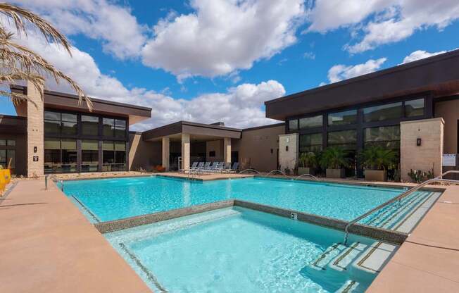 A large swimming pool in front of a building with a cloudy sky in the background.