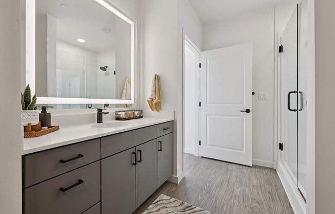 A bathroom with a white door and a mirror above the sink.