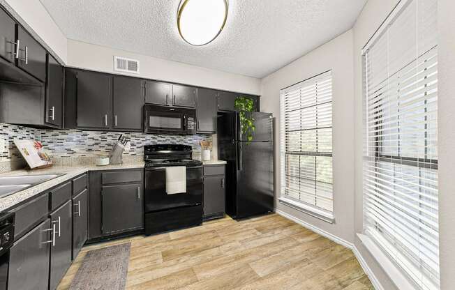 a kitchen with black cabinets and a large window