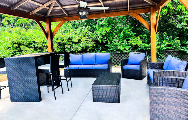 A patio with a black wicker sofa and chairs.