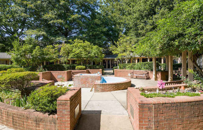 a courtyard with a pool and benches and trees